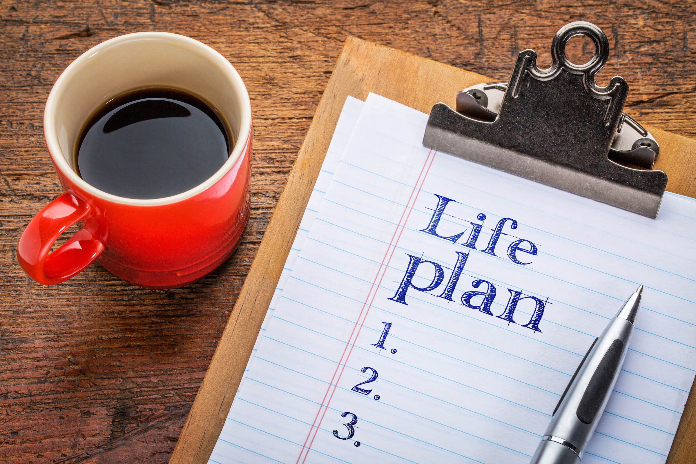 Life plan concept -a list on clipboard against grunge wood desk with a cup of coffee